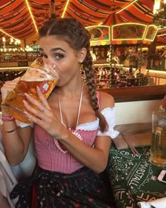 a woman sitting at a table drinking from a beer glass while wearing a diro outfit