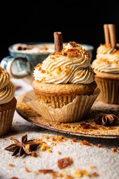 three cupcakes with white frosting and cinnamon sprinkles on a plate