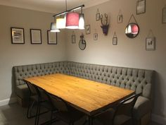 a wooden table sitting in the middle of a room next to a booth with chairs