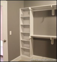 an empty white closet with shelves and doors in the room that is painted light gray