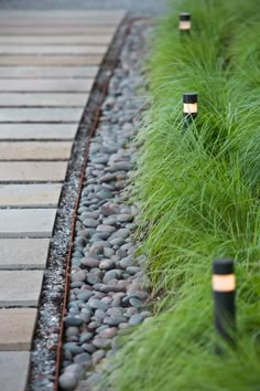 some lights that are sitting in the grass near rocks and stones, along with long grass