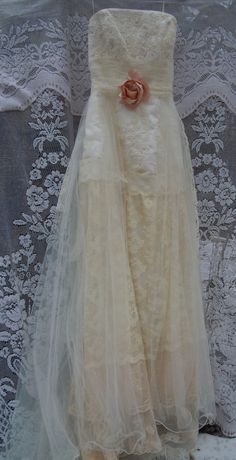 a white dress with a rose on the front and back, hanging from a lace curtain