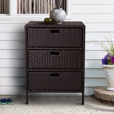 a brown wicker dresser sitting next to a white house