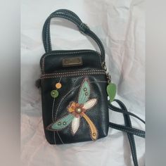 a small black purse with a dragonfly on it's side and green accents