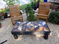 two chairs and a table made out of pallet wood sitting on gravel next to plants