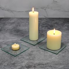 three lit candles sitting on top of glass coasters