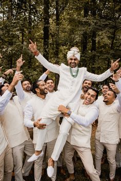 a group of men in white suits and tuxedos are posing for a photo