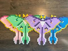 three pieces of perler bead art sitting on top of a wooden table