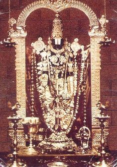 an ornate gold statue in front of a brick wall with candles on the side and other decorations around it