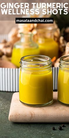 two jars filled with yellow liquid sitting on top of a cutting board