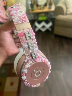 a person holding up a pink headphone with lots of beads and charms on it