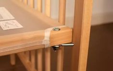 a wooden crib with a white sheet on the bottom and an ironing board attached to it