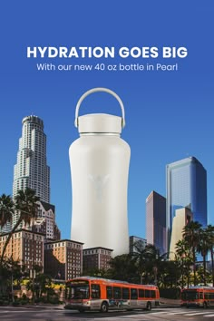 a large white water bottle sitting on top of a road next to a bus and palm trees