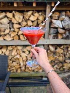 a hand holding a wine glass filled with red liquid