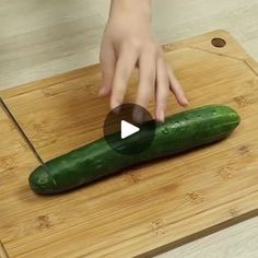 someone is cutting up a cucumber on a wooden board