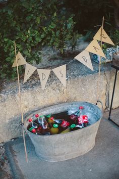 a bucket filled with soda bottles sitting on top of a cement floor next to flags