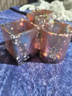 four glass cups sitting on top of a blue table cloth covered in sparkles and stars