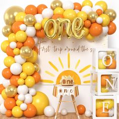 an orange, yellow and white balloon arch with the word one on it