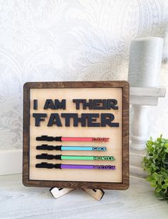 a wooden sign that says i am their father with four different colored crayons