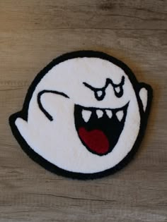 a close up of a patch on a wooden surface with an evil looking ghost face