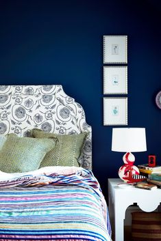 a bedroom with blue walls and colorful bedding, including a striped comforter on the headboard