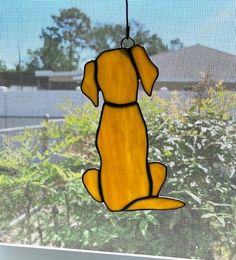 a stained glass dog ornament hanging from a window