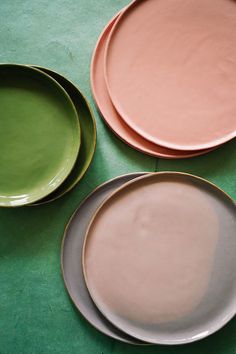 three different colored plates sitting on top of a green table