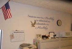 an office with a clock, desk and wall decal that says students must be healthy to be educanated to be healthy