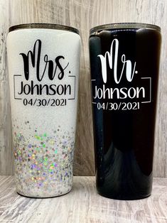 two personalized tumblers sitting next to each other on a wooden table with white and black background