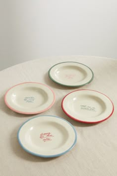 four small plates sitting on top of a white tablecloth covered table with red, blue and green trim