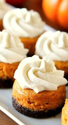 several cupcakes with white frosting on a plate next to some oranges