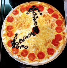 a pizza with pepperoni, olives and black olives in the shape of an e