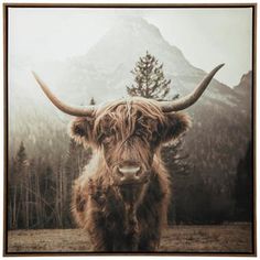 an animal with long horns standing in front of mountains