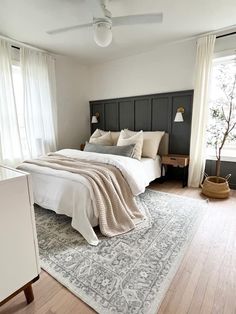 a bedroom with a bed, rug and window in the corner is shown on top of a wooden floor