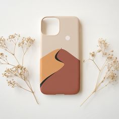 a phone case with a desert scene on it next to some flowers and dried plants