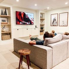 a man laying on top of a couch in a living room next to a tv