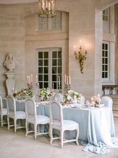 a dining room table is set with white chairs and blue linens for an elegant dinner