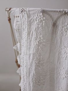 an old white crocheted blanket hanging on a clothes rack