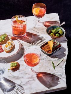 a marble table topped with plates and glasses filled with food next to drinks on top of it