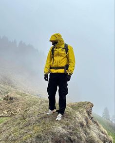 a man in yellow jacket standing on top of a hill