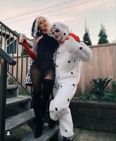 two women dressed in costumes standing on steps with one holding a stuffed animal and the other leaning against her back