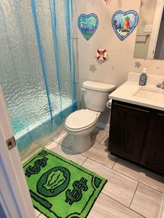 a bathroom with a green rug on the floor and blue shower curtain over the toilet