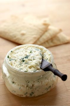 a jar filled with food sitting on top of a wooden table next to crackers