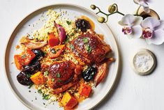 a white plate topped with meat and vegetables on top of couscouse rice