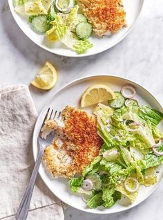 two plates filled with fish and salad on top of a white marble countertop next to each other