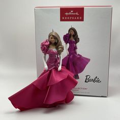 a barbie doll in a pink dress next to a box