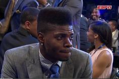 a man in a suit and tie sitting next to other people at a basketball game