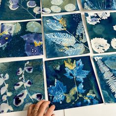 a person is working on paintings with blue and white flowers, leaves and watercolors