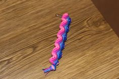 a pink and blue braided toothbrush on a wooden table