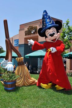 the mickey mouse mascot is standing in front of an outdoor costume shop with large pumpkins